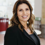 2025THA_lauracornelson - Texas Healthcare Trustees Smiling woman with shoulder length wavy brown hair wearing a black blazer in a bright indoor setting