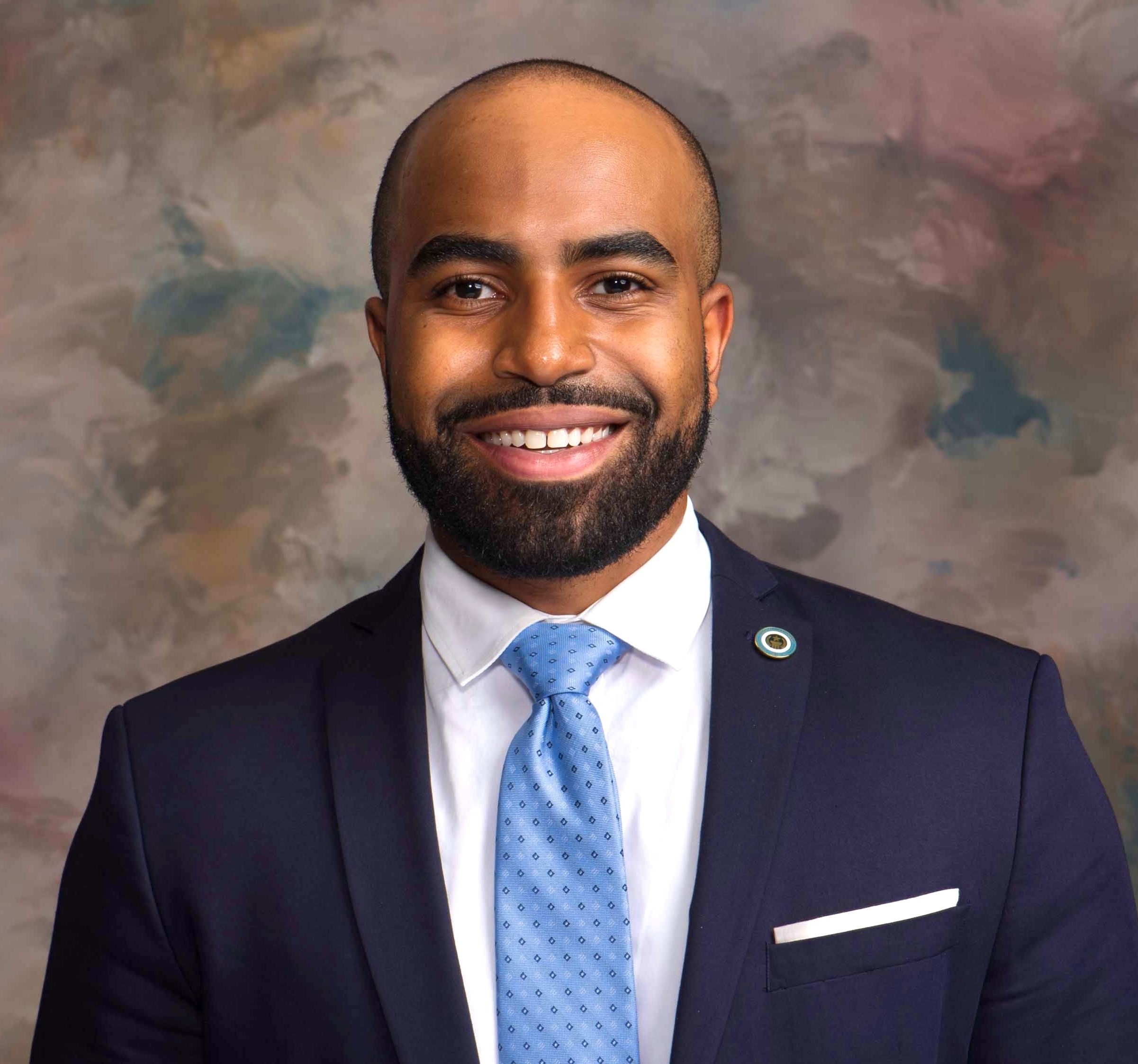 Headshot_Berry_Cornelius - Texas Healthcare Trustees Smiling man in a navy suit light blue patterned tie white shirt and lapel pin in a portrait photo