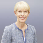 Headshot_Dixon_Laura - Texas Healthcare Trustees Smiling portrait of a blonde woman wearing a blue patterned blazer and silver jewelry