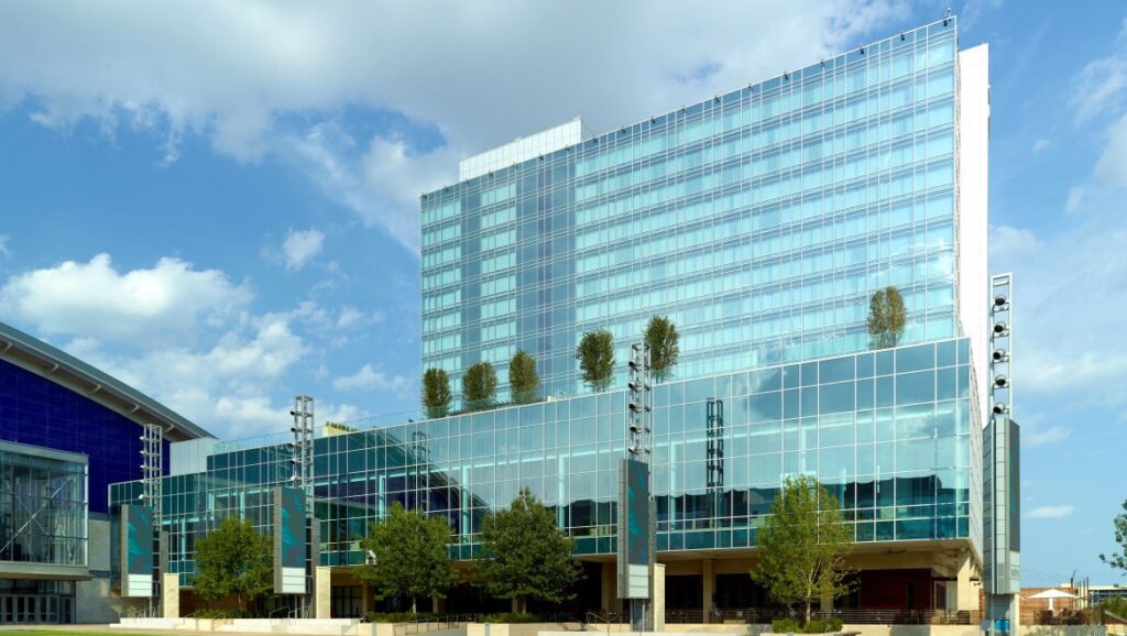 Modern glass office building with reflective facade and planter boxes on the terrace under a blue sky